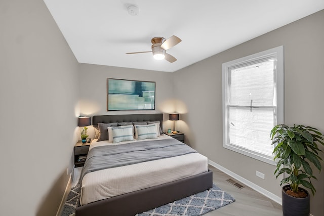 bedroom featuring light hardwood / wood-style floors, multiple windows, and ceiling fan