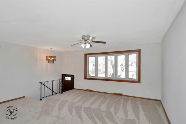 unfurnished room featuring ceiling fan with notable chandelier and light colored carpet