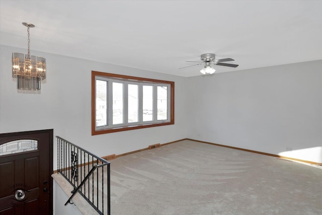 foyer featuring light carpet and ceiling fan with notable chandelier