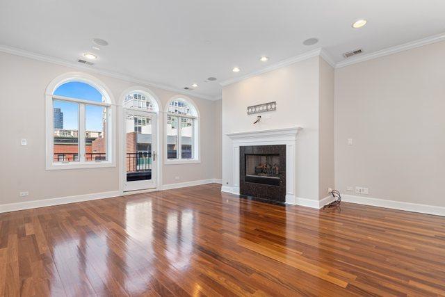 unfurnished living room featuring dark wood-type flooring and crown molding