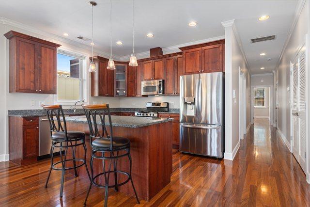 kitchen featuring a breakfast bar, stainless steel appliances, crown molding, pendant lighting, and a center island