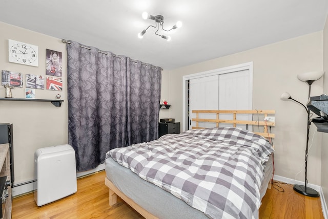 bedroom featuring light wood-type flooring, a closet, and a baseboard heating unit