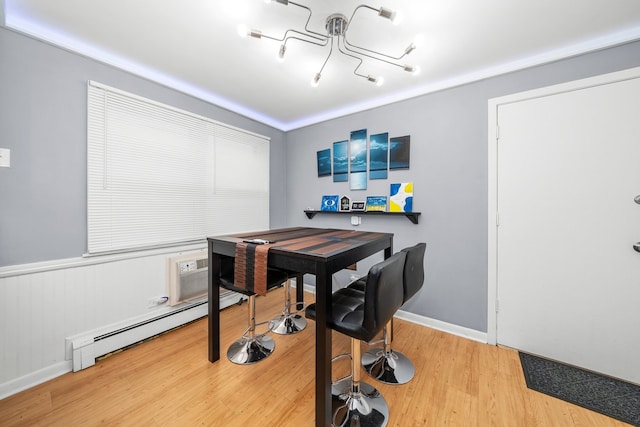 dining room featuring a wall unit AC, a baseboard heating unit, and hardwood / wood-style flooring