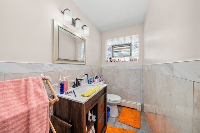 bathroom with vanity, baseboard heating, wood-type flooring, tile walls, and toilet