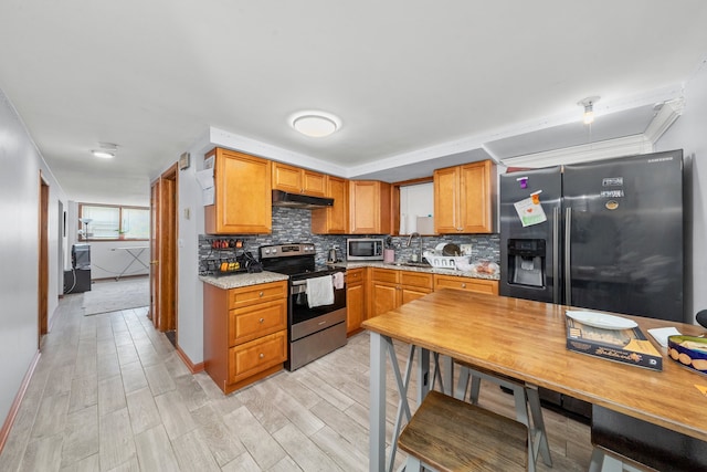 kitchen featuring appliances with stainless steel finishes, tasteful backsplash, light hardwood / wood-style flooring, and light stone counters