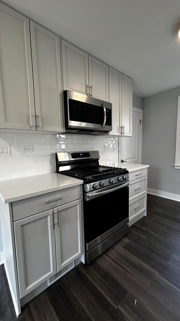 kitchen with decorative backsplash, appliances with stainless steel finishes, and dark wood-type flooring