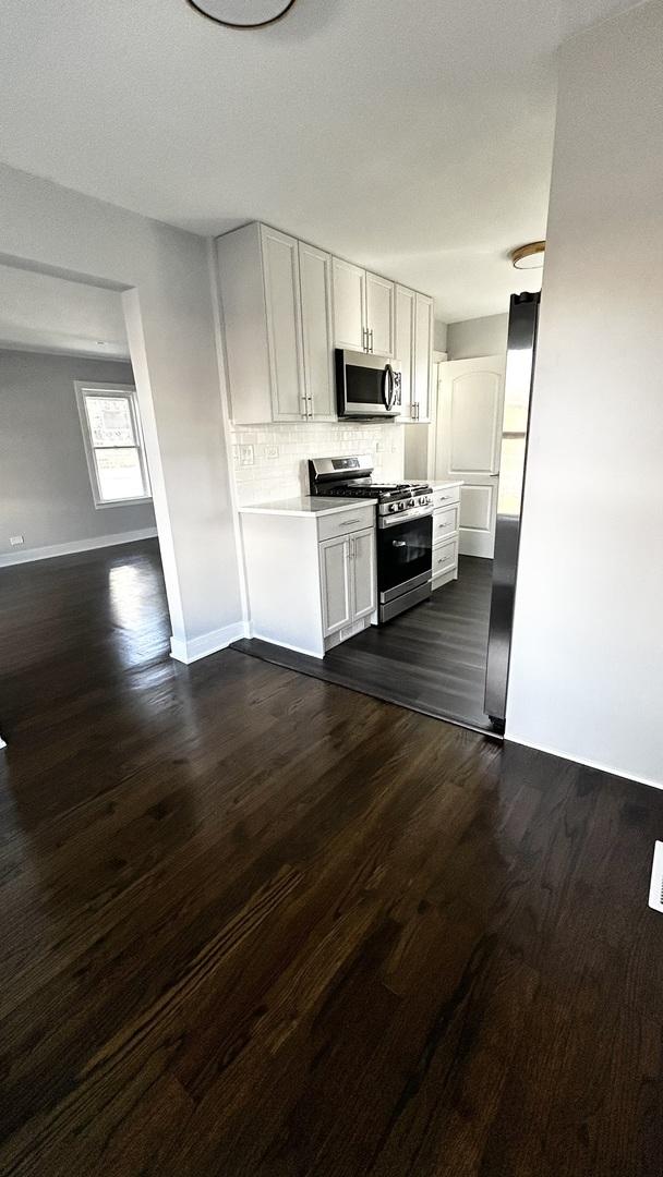 kitchen featuring white cabinets, dark hardwood / wood-style floors, decorative backsplash, and appliances with stainless steel finishes