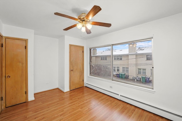 empty room featuring ceiling fan, light wood-type flooring, and a baseboard radiator