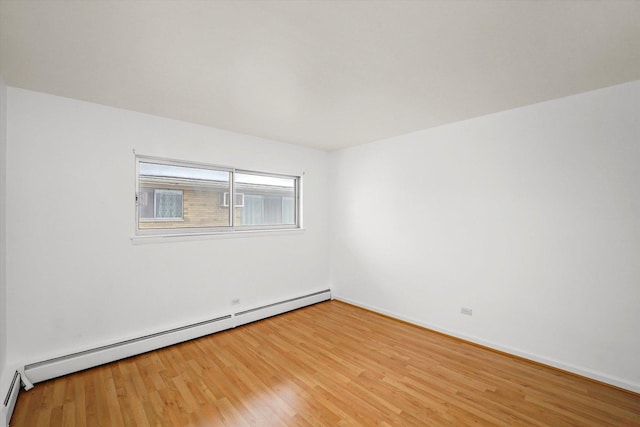 unfurnished room featuring wood-type flooring and a baseboard heating unit