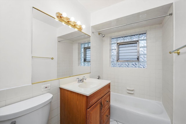 full bathroom with tiled shower / bath, vanity, tile walls, and toilet