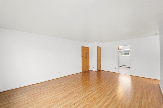 unfurnished room featuring light hardwood / wood-style floors and a baseboard heating unit