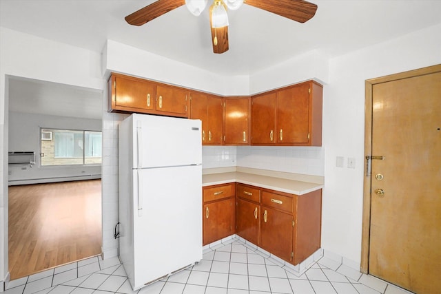 kitchen with decorative backsplash, ceiling fan, a baseboard radiator, white fridge, and light tile patterned flooring