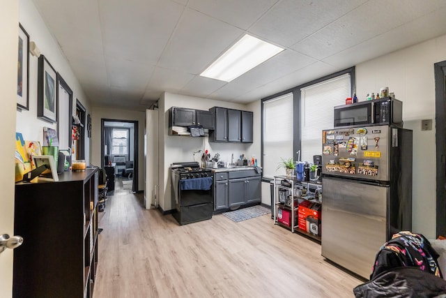 kitchen featuring gas stove, stainless steel fridge, and light hardwood / wood-style flooring