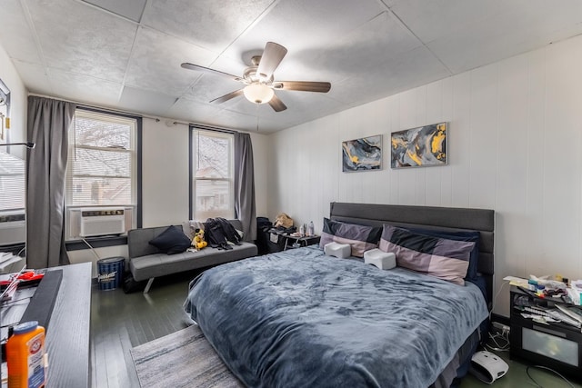 bedroom featuring ceiling fan, cooling unit, and wood-type flooring