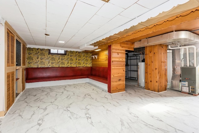 basement with wooden walls, heating unit, and water heater