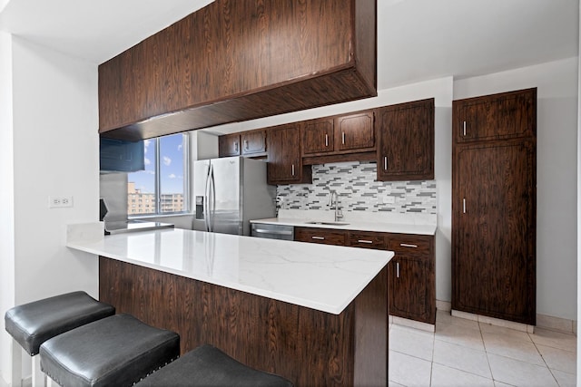 kitchen featuring a breakfast bar, backsplash, sink, appliances with stainless steel finishes, and kitchen peninsula