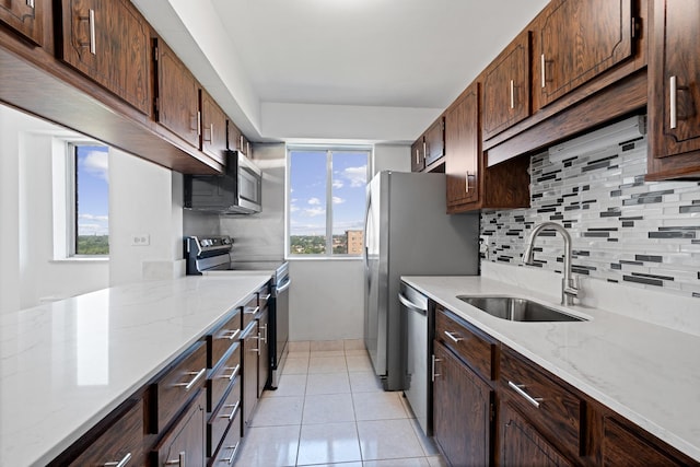 kitchen with light stone countertops, sink, light tile patterned floors, and stainless steel appliances