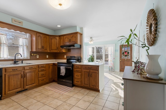 kitchen with a wealth of natural light, light tile patterned floors, sink, kitchen peninsula, and electric stove