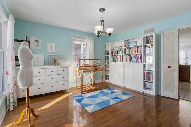 misc room featuring dark wood-type flooring and an inviting chandelier