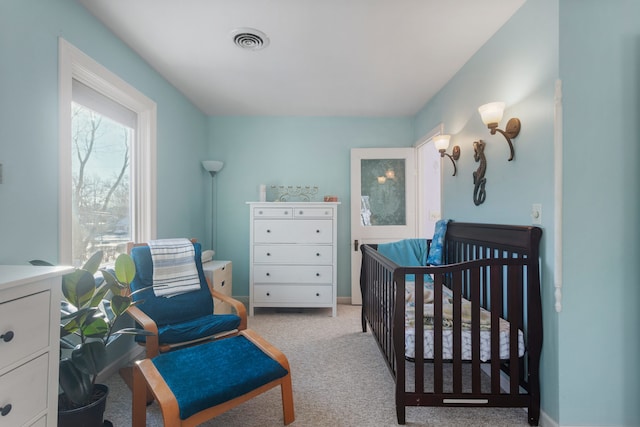 bedroom with light carpet and a nursery area