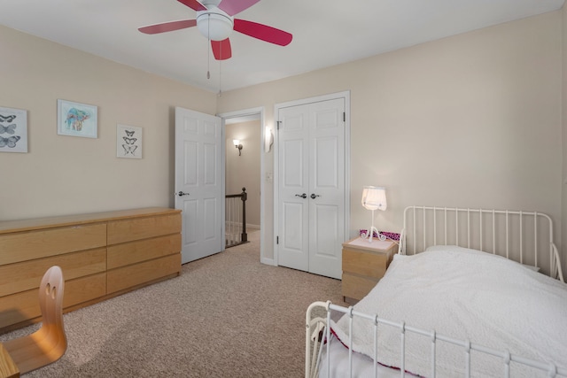 bedroom with ceiling fan, light colored carpet, and a closet