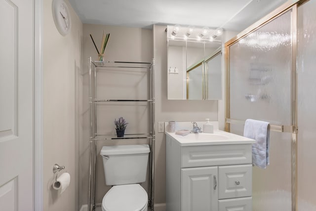 bathroom featuring vanity, toilet, and a shower with door