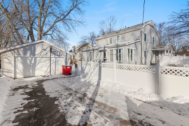 view of snowy exterior featuring a garage and an outdoor structure