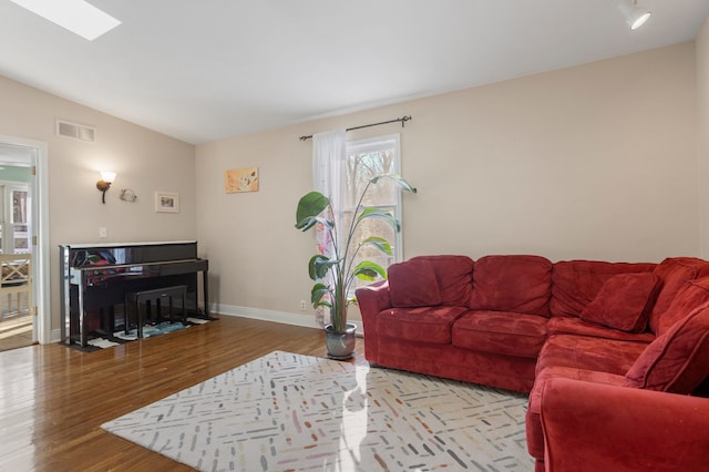 living room featuring light hardwood / wood-style floors and vaulted ceiling with skylight