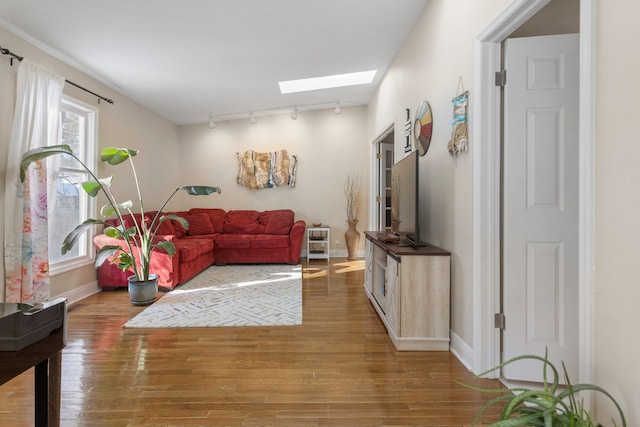 living room with rail lighting, hardwood / wood-style floors, and a skylight