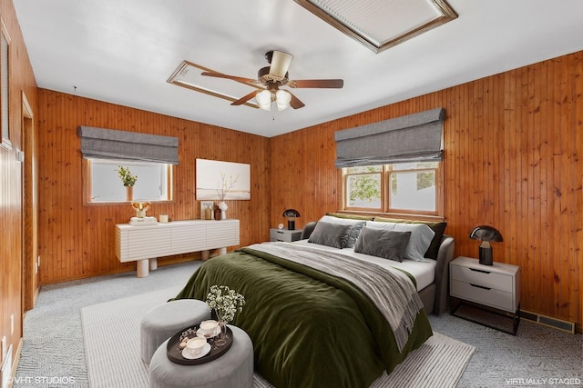 carpeted bedroom featuring ceiling fan and wood walls