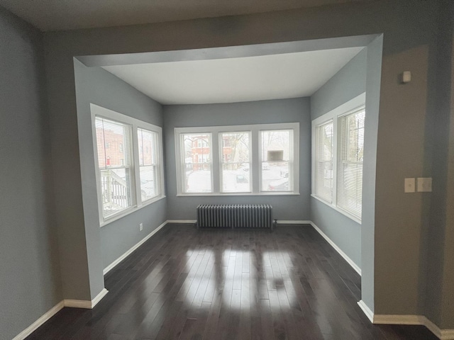 empty room with radiator heating unit and dark hardwood / wood-style flooring