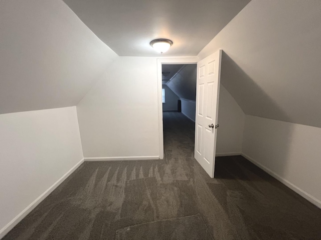 additional living space featuring vaulted ceiling and dark colored carpet