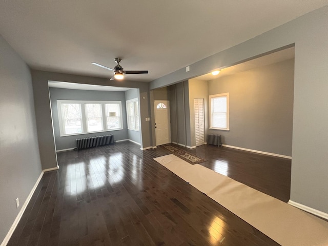 empty room with ceiling fan, dark hardwood / wood-style flooring, and radiator heating unit