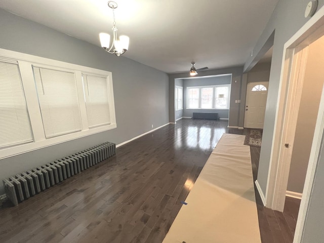 interior space with radiator, dark wood-type flooring, and ceiling fan with notable chandelier