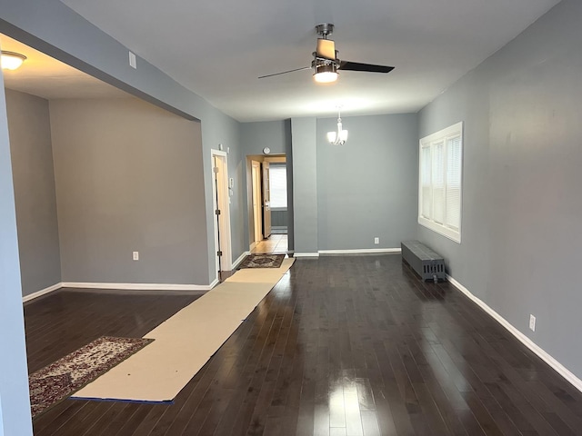 empty room with radiator, dark hardwood / wood-style flooring, and ceiling fan with notable chandelier