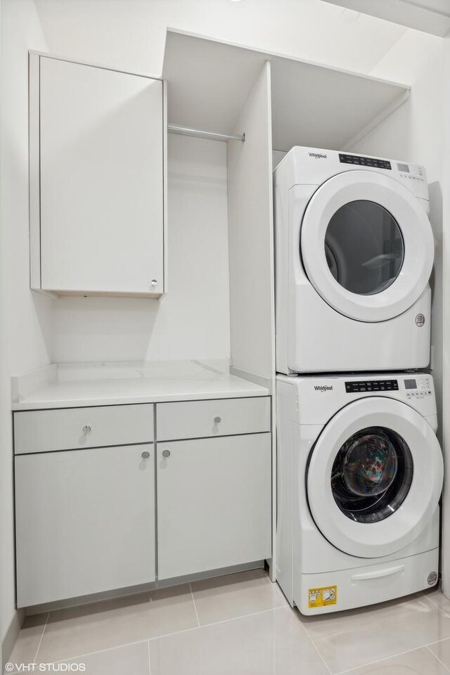 washroom with cabinets, stacked washer and clothes dryer, and light tile patterned flooring