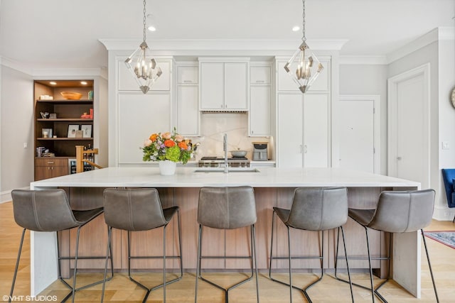 kitchen with a kitchen breakfast bar, light hardwood / wood-style floors, a spacious island, and white cabinetry