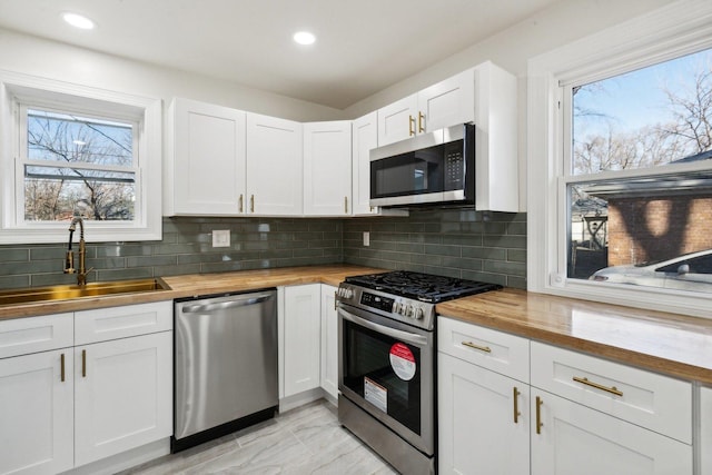 kitchen featuring butcher block counters, white cabinetry, sink, and stainless steel appliances