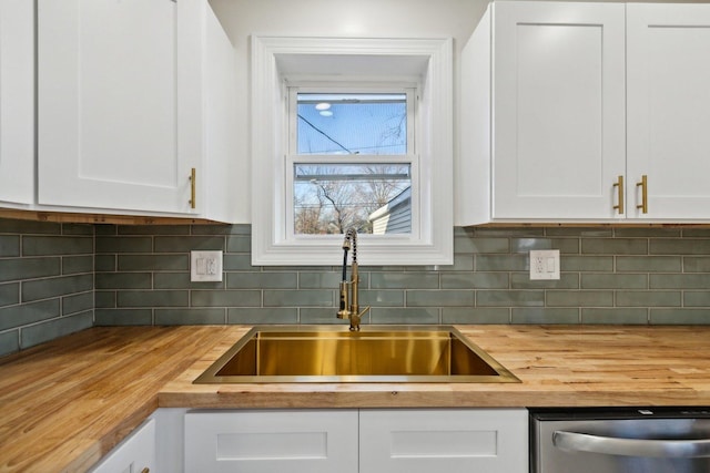 kitchen featuring white cabinets, tasteful backsplash, stainless steel dishwasher, and sink