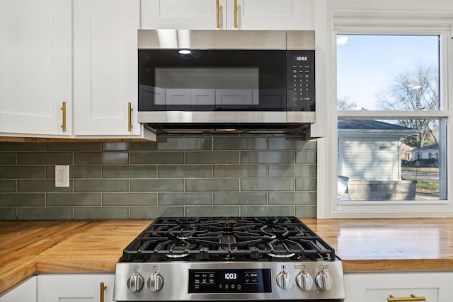 kitchen featuring stainless steel appliances, white cabinetry, tasteful backsplash, and butcher block counters