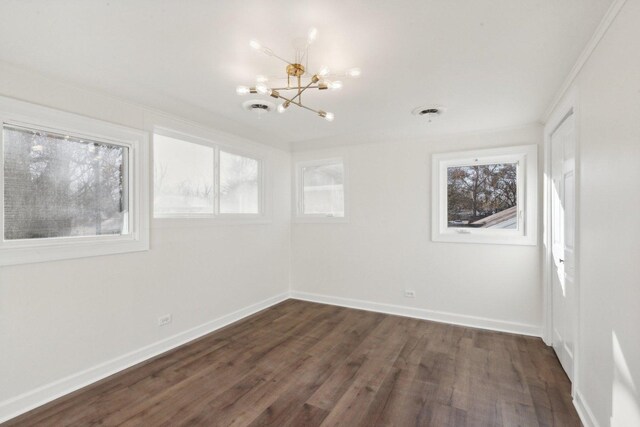 empty room with a notable chandelier, crown molding, and dark wood-type flooring