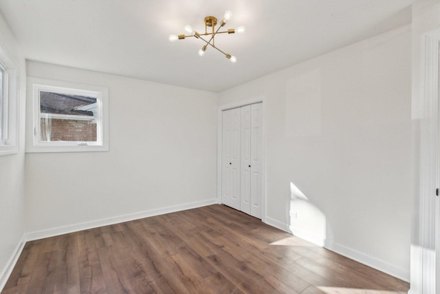 unfurnished room with a chandelier and dark hardwood / wood-style flooring