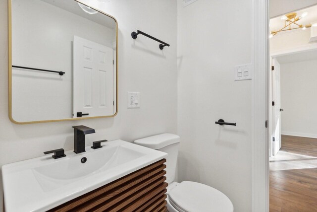 bathroom featuring toilet, hardwood / wood-style floors, vanity, and an inviting chandelier