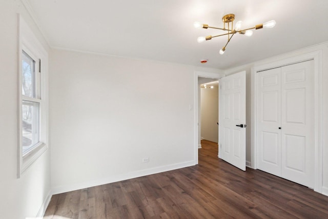 unfurnished bedroom with dark hardwood / wood-style floors, an inviting chandelier, a closet, and ornamental molding