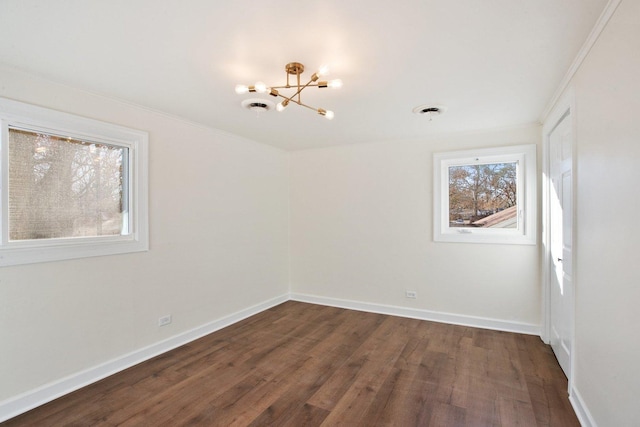 empty room with dark hardwood / wood-style floors, crown molding, and an inviting chandelier