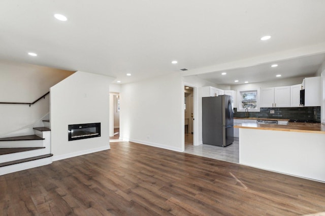 kitchen with white cabinetry, stainless steel appliances, butcher block countertops, decorative backsplash, and hardwood / wood-style flooring