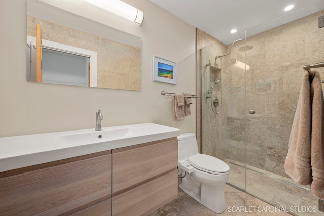 bathroom with vanity, tiled shower, and toilet