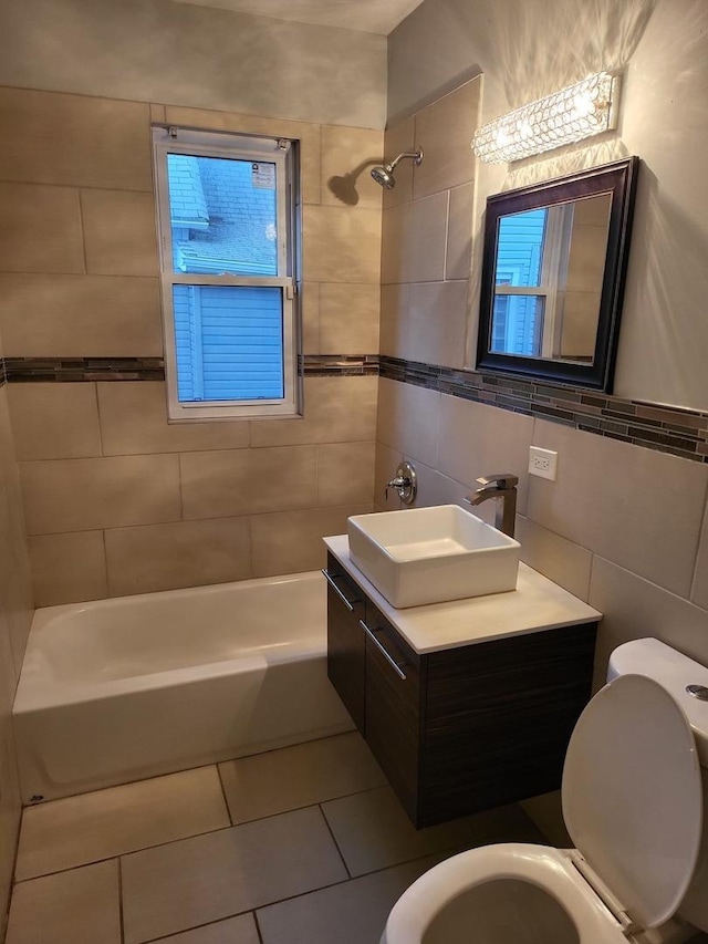 full bathroom featuring tile patterned flooring, toilet, vanity, tile walls, and tiled shower / bath