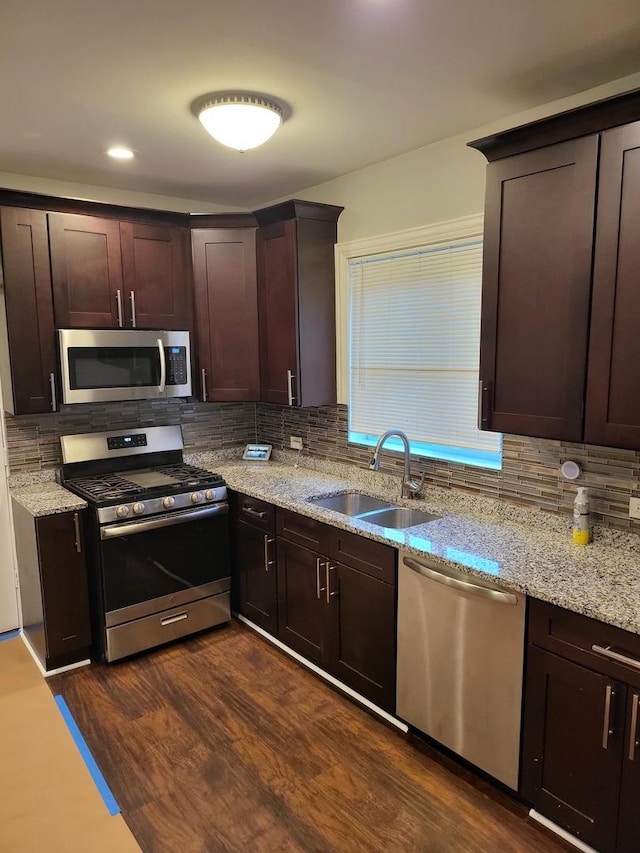 kitchen featuring decorative backsplash, appliances with stainless steel finishes, dark brown cabinetry, sink, and dark hardwood / wood-style floors