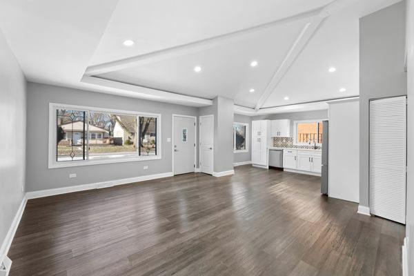 unfurnished living room featuring dark hardwood / wood-style floors and vaulted ceiling